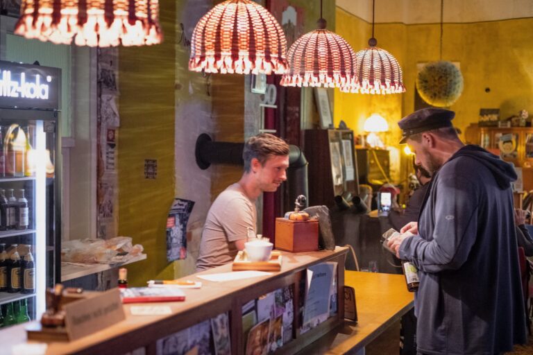 Tresen des Cafés mit Gästen unter Glasperlen-Lampen